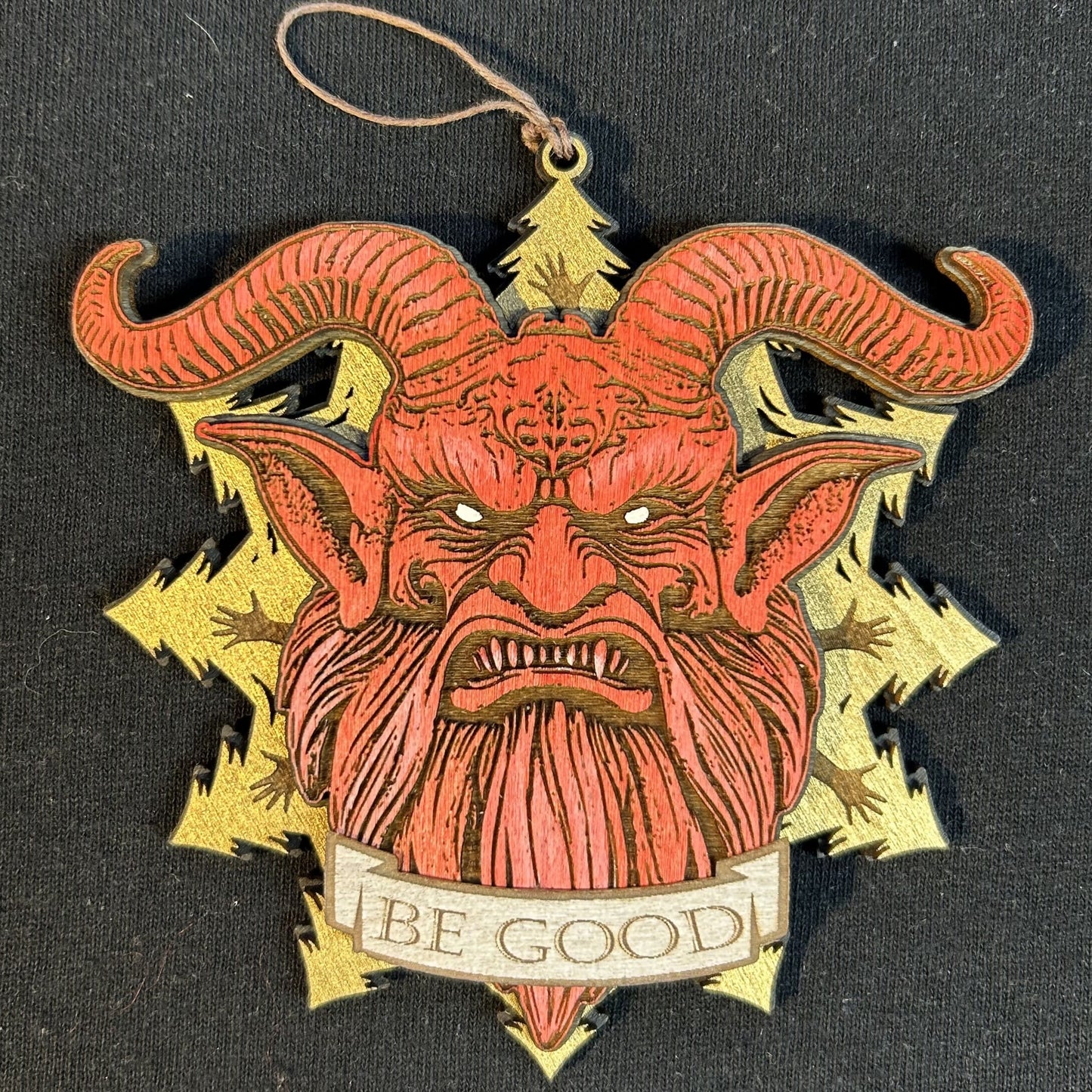 Decorative ornament with a red face and gold horns on a black background