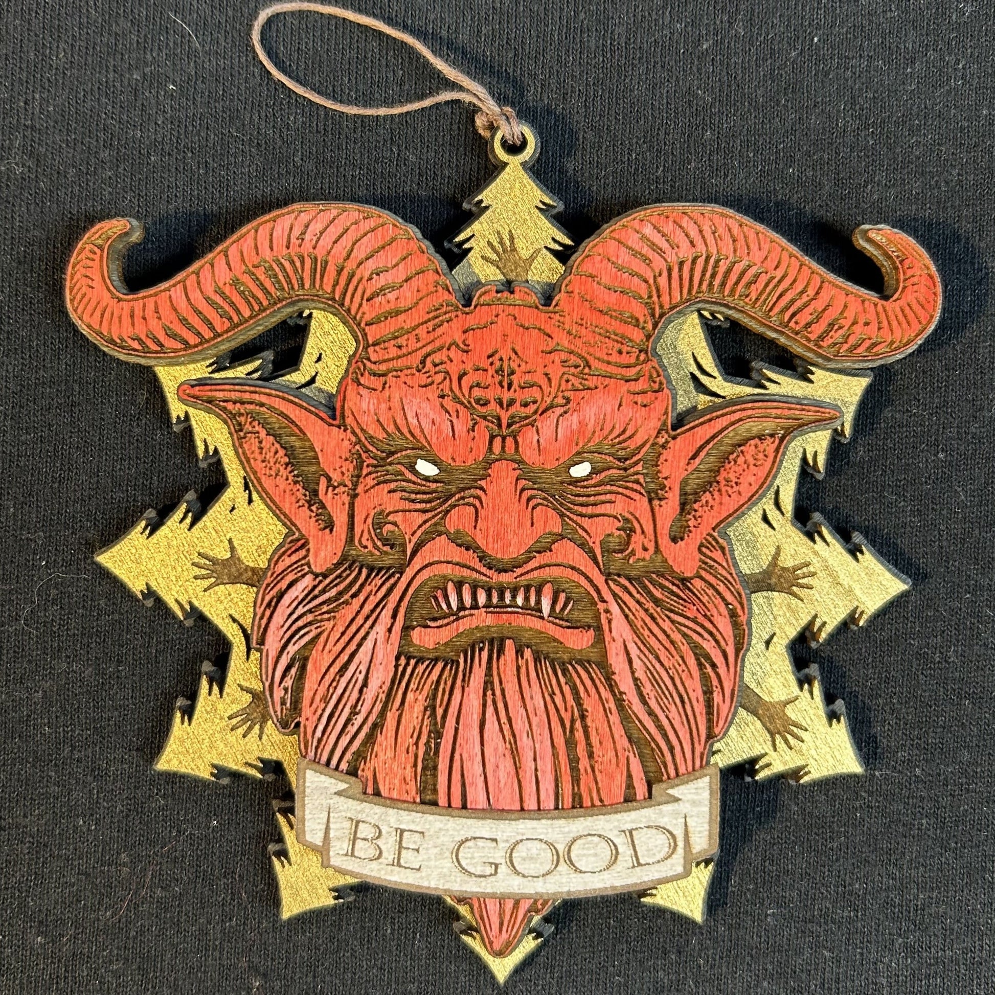 Decorative ornament with a red face and gold horns on a black background