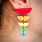 Colorful half-circle earrings on an ear with a neutral background