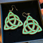 Celtic knot earrings in a black box held by a hand.